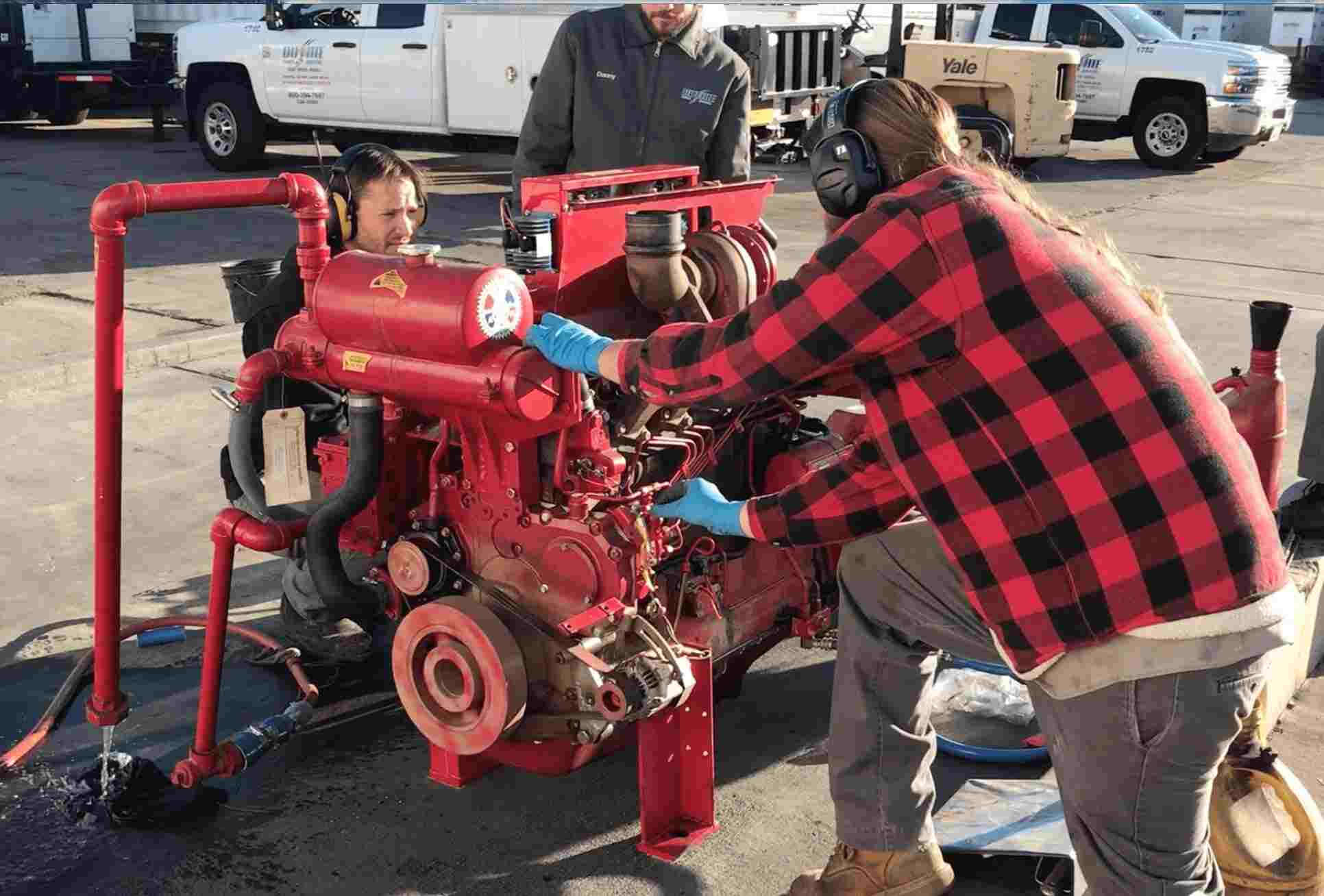 Generator Technician in a red and black flannel servicing a diesel fire pump engine.