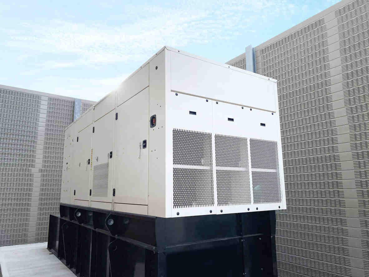 White commercial standby generator in an outdoor enclosure.