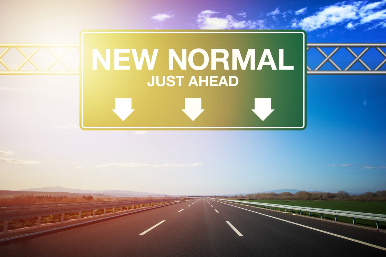 Freeway sign on an empty highway saying "New Normal Just Ahead."