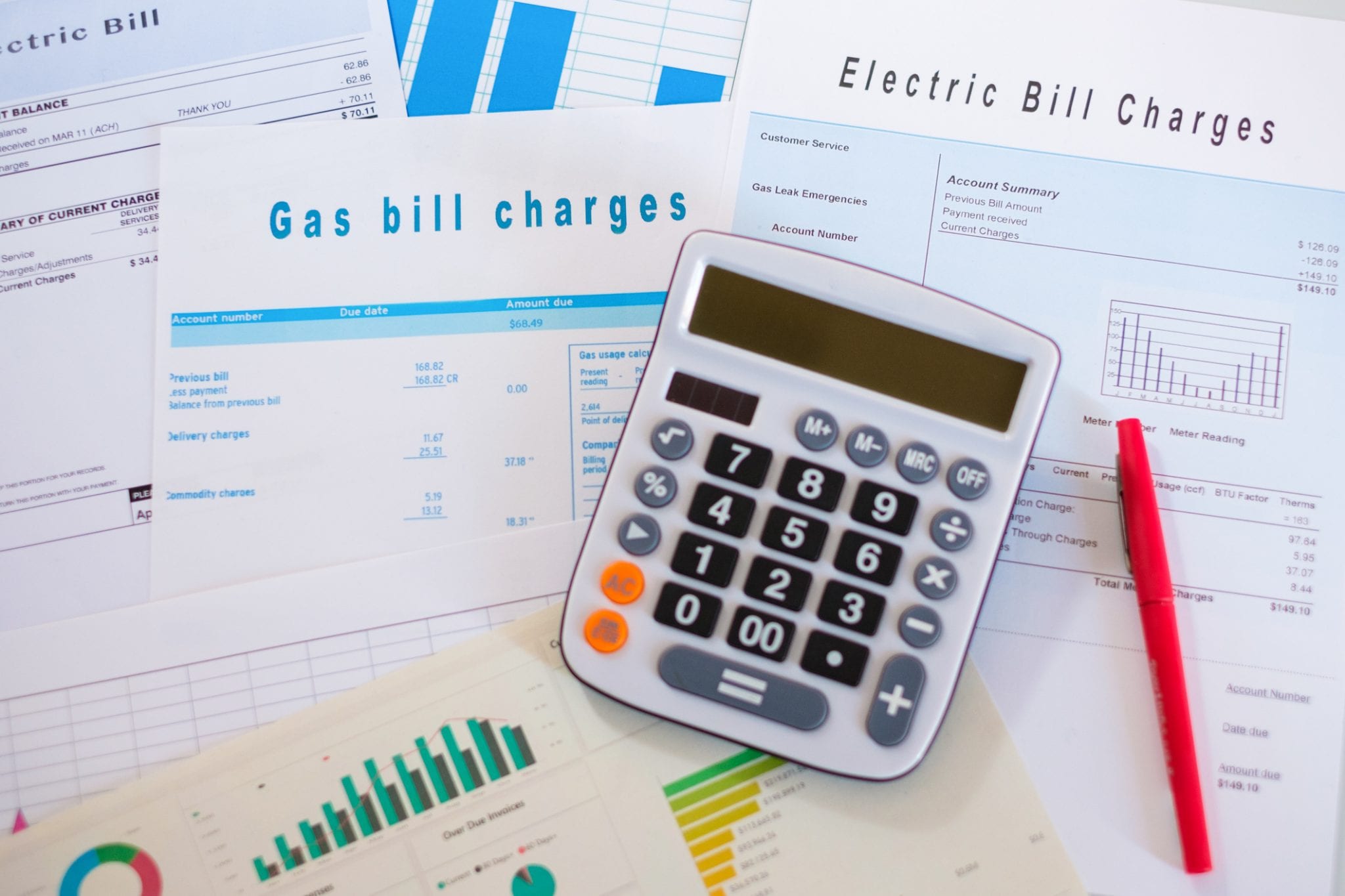 Desk calculator with invoices for energy and electric bills as elements of calculating a generator maintenance budget.