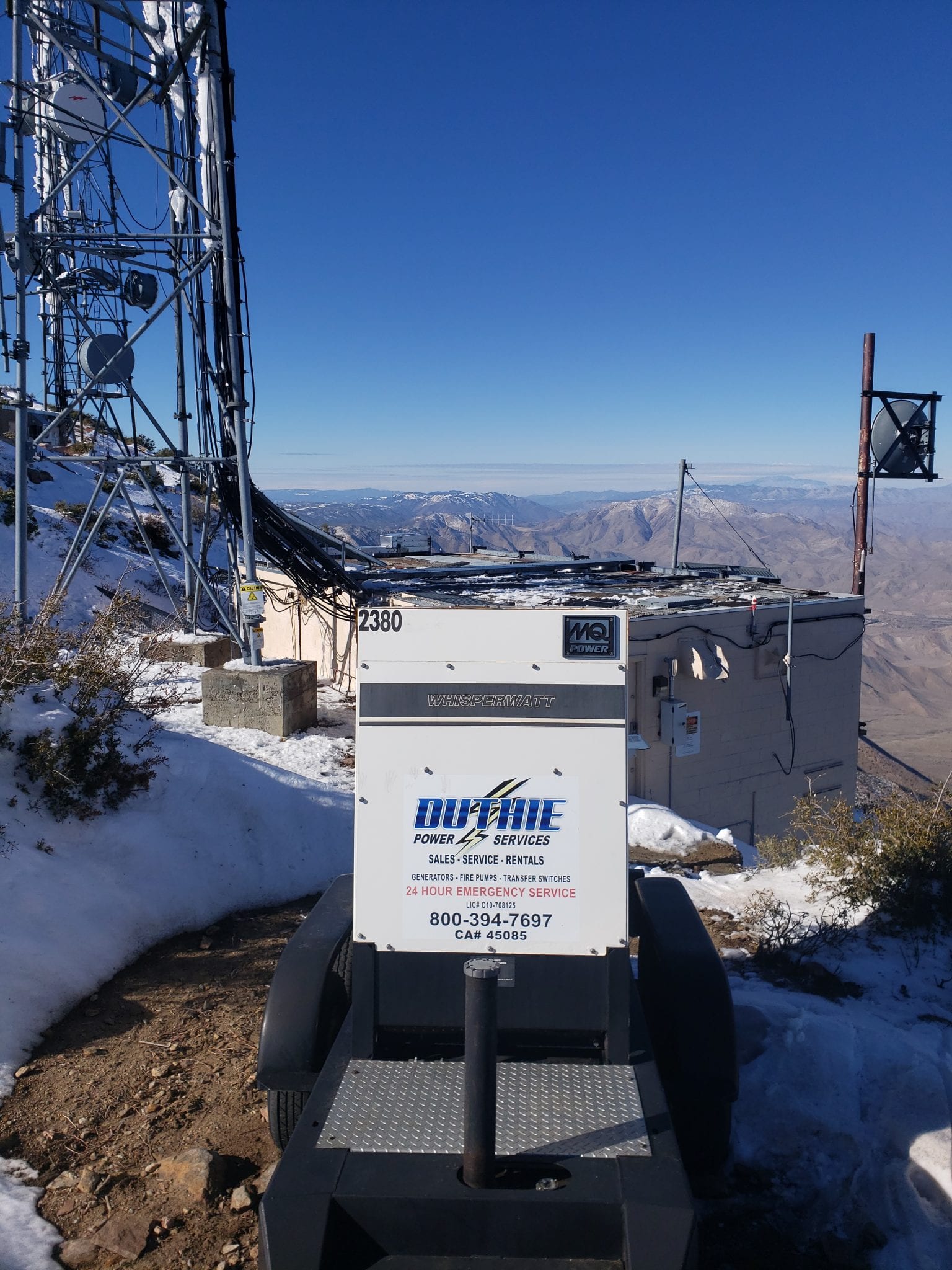 Duthie Power Services rental generator on a snowy mountaintop overlooking a valley.