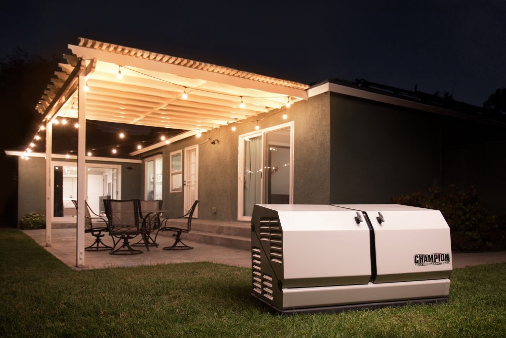 Champion home generator in the back yard of a home with a patio, patio furniture and outdoor lights.