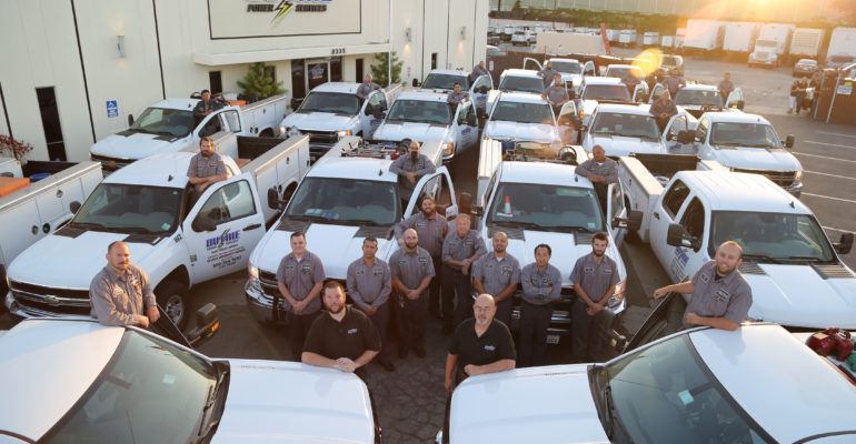 The Duthie Power Services family of employees standing next to generator service trucks.